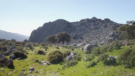 Distant-hikers-walk-through-rocky-countryside-in-mountains-of-Cadiz,-Spain