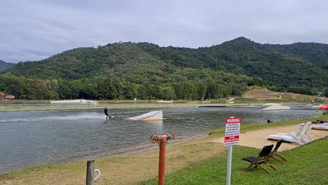 Adult-Being-Pulled-By-Rope-And-Jumping-Ramp-At-Wakeboarding-Park