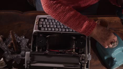 Novelist-with-whiskey-and-cigar-calls-on-phone-then-loads-typewriter-to-write