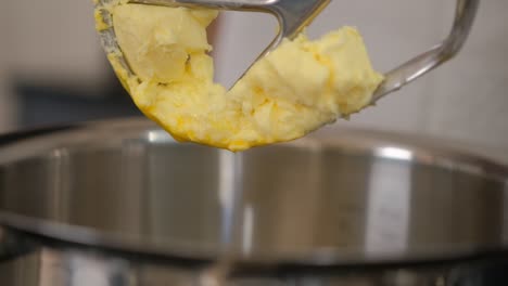 Close-up-of-raising-the-dough-covered-beater-out-of-an-electric-mixer-while-baking