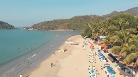 Aerial-4k-drone-footage-of-visitors-enjoying-a-tropical-beach-of-Palolem,-India