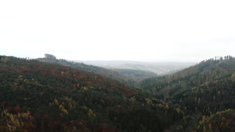Ascending-aerial-view-over-forest-covered-valley-on-foggy-day