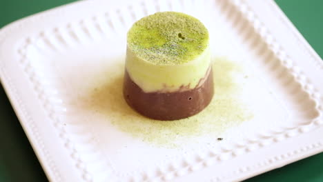 Matcha-Flavoured-Mini-Chocolate-Cake-In-A-Rotating-Square-Plate-Dusted-With-Matcha-Powder,-close-up