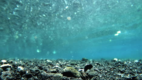Underwater-shot-of-blue-glittering-water-and-stony-sea-bed-in-Hawaii