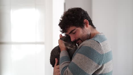 Young-adult-man-kissing-and-hugging-his-cat-with-tender
