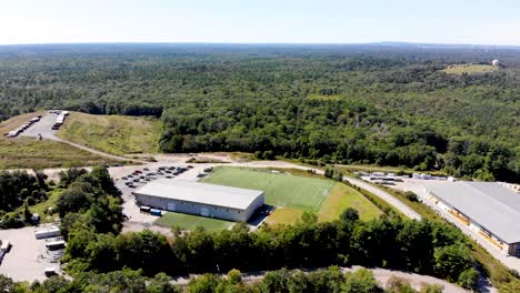 A-still-drone-view-of-a-soccer-field-and-sports-facility-that-backs-up-to-a-lush,-expansive-forest