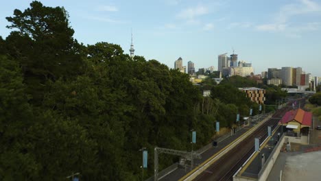 Amazing-Auckland-Skyline-Revealed-Behind-Green-Trees,-Train-Station