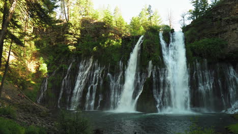 Panoramic-view-of-Burney-Falls,-forest-waterfall-in-California,-with-water-falling-down-a-mossy-cliff