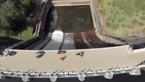 Bird's-eye-view-of-Mattupetty-Dam-and-crossing-tourists-near-Munnar-in-South-India---Aerial-top-view-tilt-up-reveal