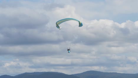 Person-Gleitschirmfliegen-über-Bewaldeten-Bergen-Mit-Weißen-Wolken-Im-Hintergrund---Rosins-Lookout-In-Scenic-Rim,-Qld,-Australien