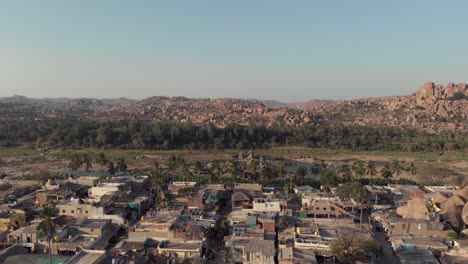 Hampi-town's-edge-with-old-buildings-contrasting-with-the-rocky-landscape-in-Karnataka,-India---Aerial-Panoramic-shot