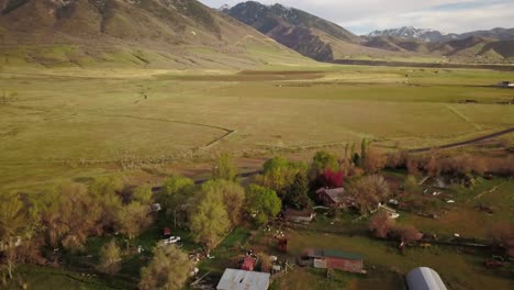 Drone-view-of-a-ranchers-land-with-a-sun-setting-behind-the-mountain-range