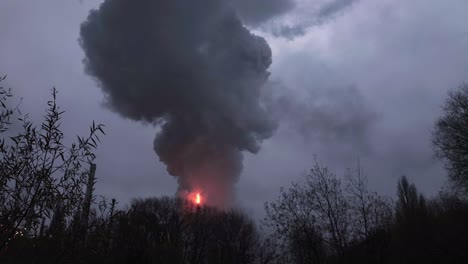 Industrial-fire-from-a-chimney-resulting-in-black-hot-smoke-pushed-into-the-air-on-a-cloudy-grey-day