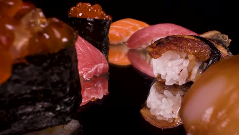 macro-view-moving-past-nigiri-sushi-on-reflective-black-glass,-toro-tuna,-salmon,-ikura,-lemon-fish-and-unagi,-hand-formed-Japanese-food