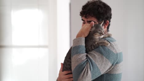 Young-adult-man-hugging-his-cat-with-tender