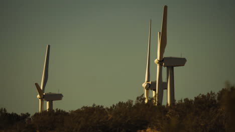 Ständige-Nahaufnahme-Von-Rotoren-Und-Flügeln-Von-Windkraftanlagen-In-Einem-Windpark-Mit-Hügel-Im-Vordergrund-In-Der-Nähe-Von-Palm-Springs-In-Der-Mojave-Wüste,-Kalifornien,-USA