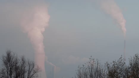 Cooling-tower-and-smokestack-release-smoke-or-steam-in-the-background