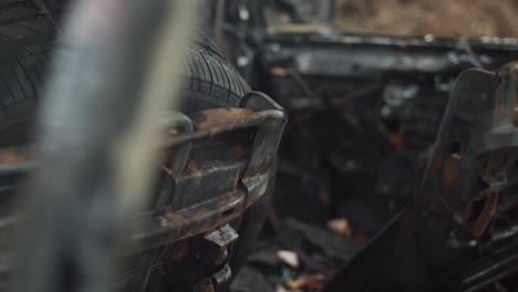 Interior-of-burned-out-car-with-tire-on-rusted-seat,-Closeup-Handheld-Detail-Pan
