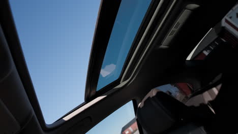 Caucasian-Scandinavian-hands-opening-hatch-sun-glass-roof-window-revealing-blue-cloudy-sky-letting-out-hot-air-wind-blowing-breeze-on-road-trip-vacation-taking-fresh-breath-air-hot-sweaty-2021-summer