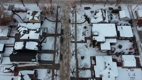 1-5-twilight-aerial-birds-eye-view-over-luxury-winter-residential-homes-snowed-in-roads-bare-trees-hardly-nobody-outside-accept-parked-cars-delivery-bikes-out-during-quiet-restriction-lockdown-COVID19