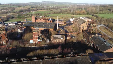 Abandoned-run-down-English-historical-industrial-coal-mine-factory-buildings-aerial-right-orbit-view