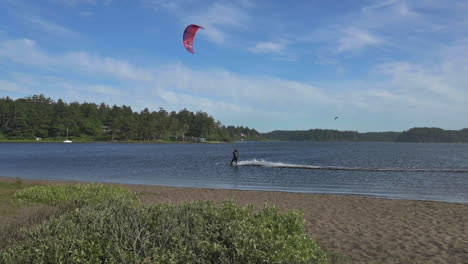 Tourist-Kitesurfing-Through-Blue-Ocean-During-Summer-In-Floras-Lake,-Oregon---Slow-Motion