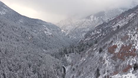 Utah-mountainous-valley-forest-covered-in-snow,-winter-aerial-landscape