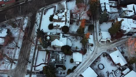 2-2-aerial-forward-birds-eye-view-over-winter-urban-luxury-home-during-a-sunset-tree-tip-lit-branches-with-wet-snowy-slushed-roads-light-traffic-in-a-rich-residential-community-with-curvy-sideroads