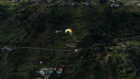Paraglider-above-rural-coastline-of-idyllic-Madeira-Island,-aerial