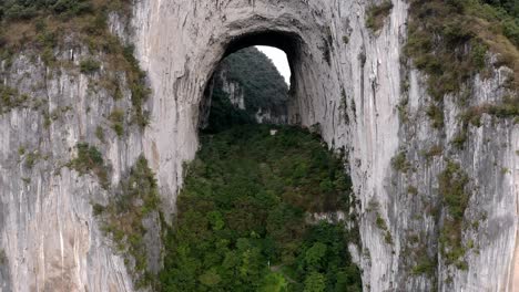 Amazing-natural-archway-in-China-karst-mountain,-Great-Arch-of-Getu,-aerial-view