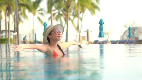 Happy-Young-Asian-Woman-Raising-Hand-in-Swimming-Pool,-Enjoying-in-Nice-Weather-and-Summer-Holiday,-Full-Frame