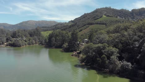 Aerial-4k-drone-footage-flying-over-a-lake-in-a-vast-valley-of-the-Western-Ghats-mountain-range-near-the-countryside-tea-plantation-town-of-Munnar,-India