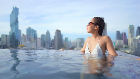 Young-Asian-woman-relaxing-in-pool-with-skyscrapers-in-background
