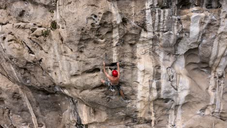 Male-rock-climber-hanging-off-rock-face,-attached-by-harness-on-karst-mountain