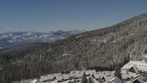 Slovenia-Pohorje-mountains-with-Lukov-dom-ski-hotel-and-cabins-covered-by-snow-right,-Aerial-pan-left-shot