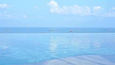 Surface-Water-From-Infinity-Swimming-Pool,-Boats-in-the-Sea-Background