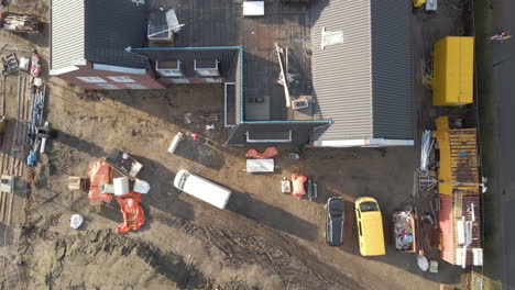 Top-down-aerial-of-construction-worker-with-wheelbarrow-walking-on-construction-site---drone-setting-down