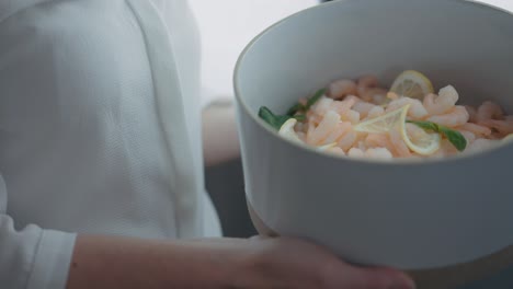 Bowl-of-shrimps-with-lemons-held-by-a-person