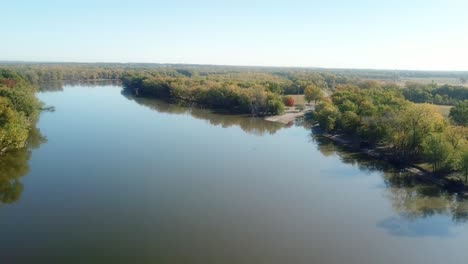 Low-angle,-slow-drone-view-of-the-Iowa-River-and-River-Trail-moving-toward-a-boat-ramp-and-campground-on-a-sunny-late-summer-day