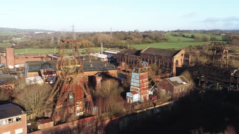 Abandoned-run-down-Staffordshire-old-rusted-historical-industrial-coal-mine-buildings-aerial-view-orbit-right