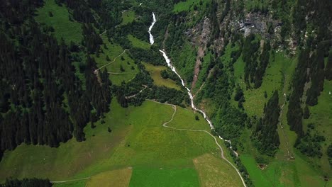 Aerial-view-of-Walcherfall-waterfall,-Ferleiten,-Austria,-flowing-down-near-a-mountain-trail