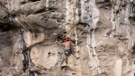 Male-rock-climber-belaying-rope-on-harness-hook-on-karst-mountain,-aerial