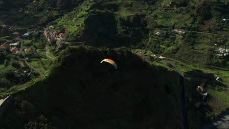 Paraglider-with-colorful-wing-floats-in-air-above-pristine-coastline-of-Madeira