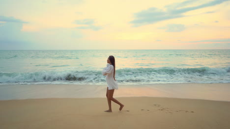 A-lovely-young-woman-walks-along-a-sandy-beach-leaves-footprints-that-are-soon-washed-away-by-the-incoming-waves