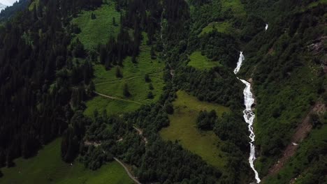 Drone-view-of-Walcherfall-waterfall,-Ferleiten,-Austria,-flowing-down-near-a-mountain-trail