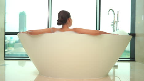Rear-View-of-Unrecognizable-Female-Sitting-in-Luxurious-Bathtub