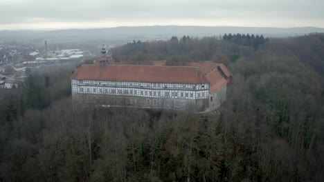 Vista-Aérea-De-Drones-Del-Tradicional-Pueblo-Alemán-Herzberg-Am-Harz-En-El-Famoso-Parque-Nacional-En-Alemania-Central-En-Un-Día-Nublado-En-Invierno.