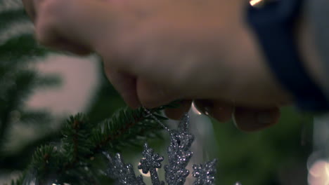 Hand-hanging-Christmas-tree-decoration,-close-up
