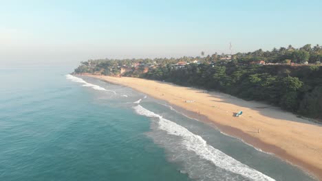 Varkala-Beach,-backed-by-palm-covered-red-cliffs