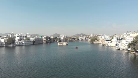 Overview-of-Pichola-Lake-to-the-Mohan-Mandir-Temple-in-Udaipur,-in-Rajasthan,-India---Aerial-Low-angle-Fly-over-shot